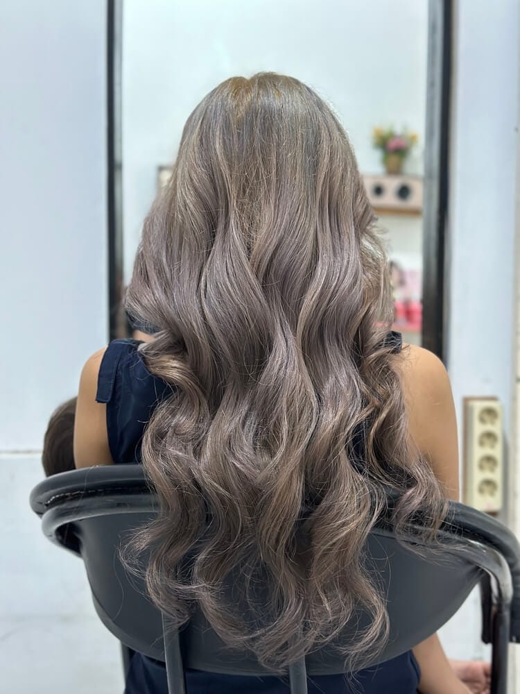 A woman with long, curly ash blonde hair.